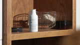Wooden shelf with various items including a white bottle, green glass bottle, and black containers in a bathroom setting.
